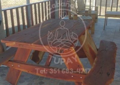 Mesa de madera maciza tipo picnic ubicada en la galería techada, ideal para desayunos o asados al aire libre.