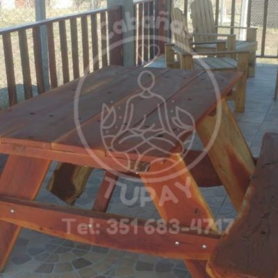 Mesa de madera maciza tipo picnic ubicada en la galería techada, ideal para desayunos o asados al aire libre.