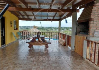 Galería techada privada con asador parrilla y mesa de madera con vistas panorámicas a las sierras en Cabaña Green, Villa Parque Siquiman.